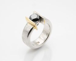 Dieser Ring wurde von einer Teilnehmerin in einem Goldschmiedekurs gefertigt. Der Ring besteht aus Silber mit einem schwarzen Diamanten. Um Akzente zu setzten wurden Teile vergoldet.